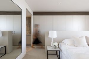 Contemporary bedroom with white walls, mirror, and bedside lamp.