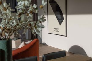 Stylish dining area with modern artwork, green plant and orange accent chair.
