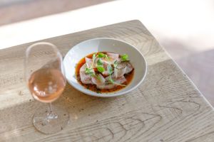 Elegant plated dish with wine glass on wooden table in natural lighting.