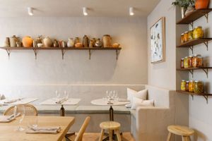 Rustic dining space with wooden shelf displaying terracotta pots and minimal seating arrangement.
