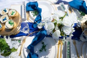 Close-up of decorated dessert table with white roses and royal blue accents.