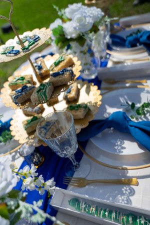 Detailed view of elegant table setting with cupcakes, crystal glasses and blue table decor.