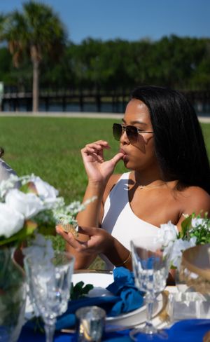 Outdoor dining scene with crystal glasses and white floral centerpieces on a sunny day.