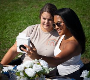 People enjoying a casual outdoor meal at a decorated table with white flowers.