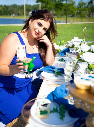 An elegant outdoor table setting with blue and white decor near a lake.