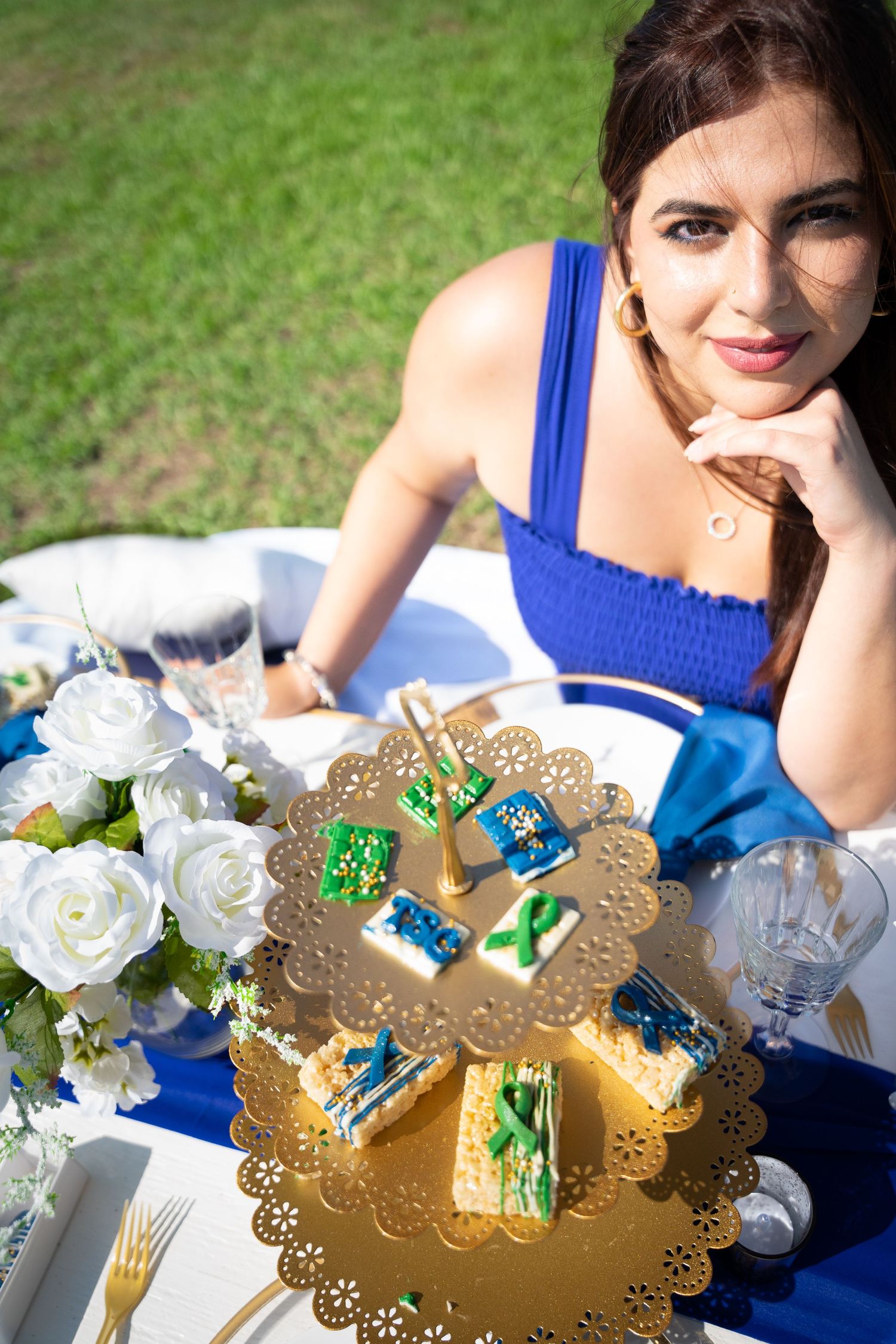 Ornate gold decorative plates with white floral arrangements on an outdoor table setting.