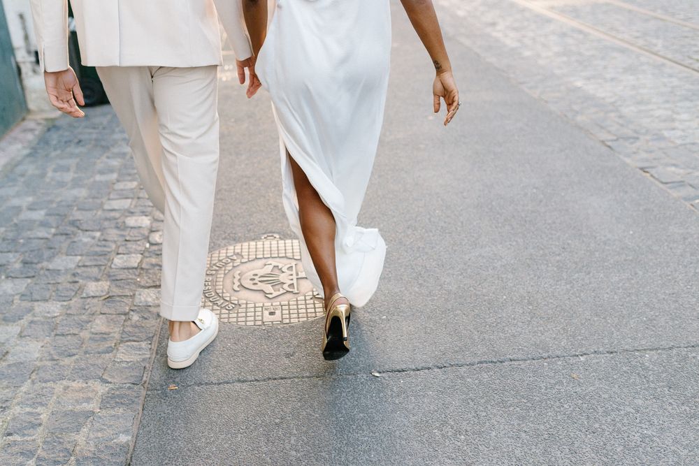 Close-up view of couple's feet walking together, wearing white outfits and contrasting footwear.