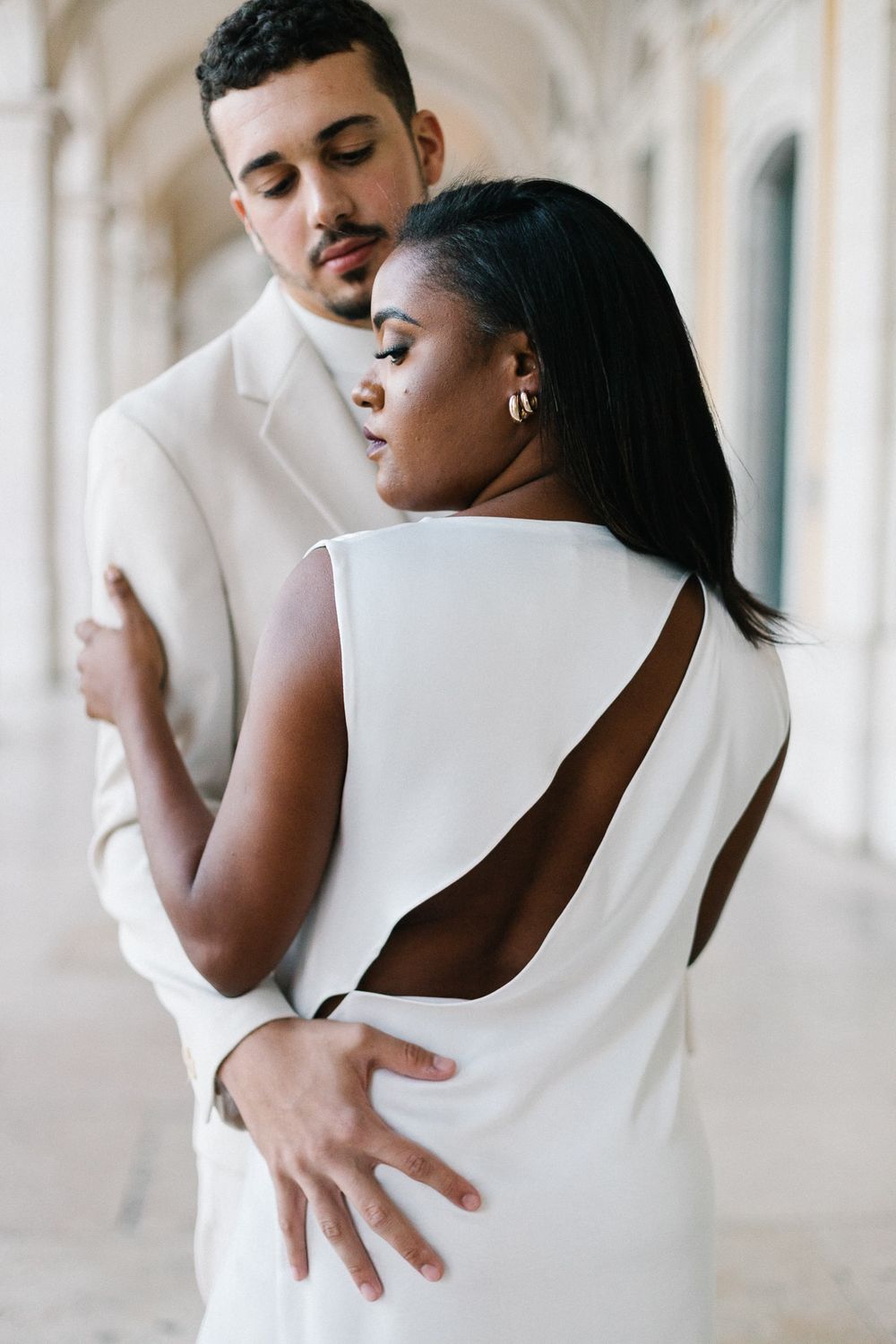 Close-up of couple in white attire showing elegant backless dress detail.