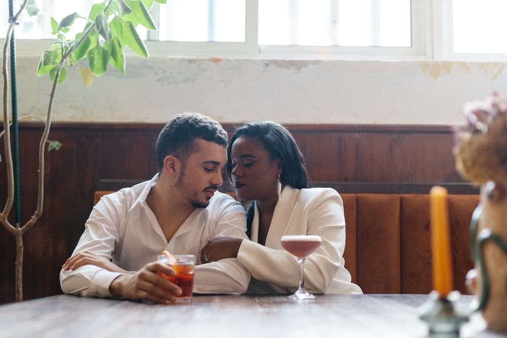 Couple sharing an intimate moment at a rustic restaurant booth with drinks.