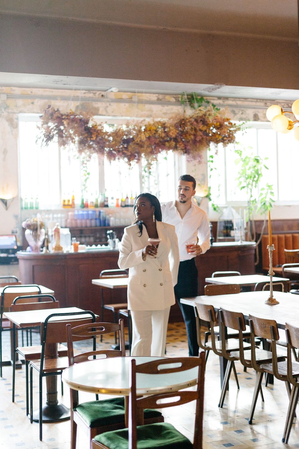 Couple standing in restaurant with floral ceiling installation and vintage decor.