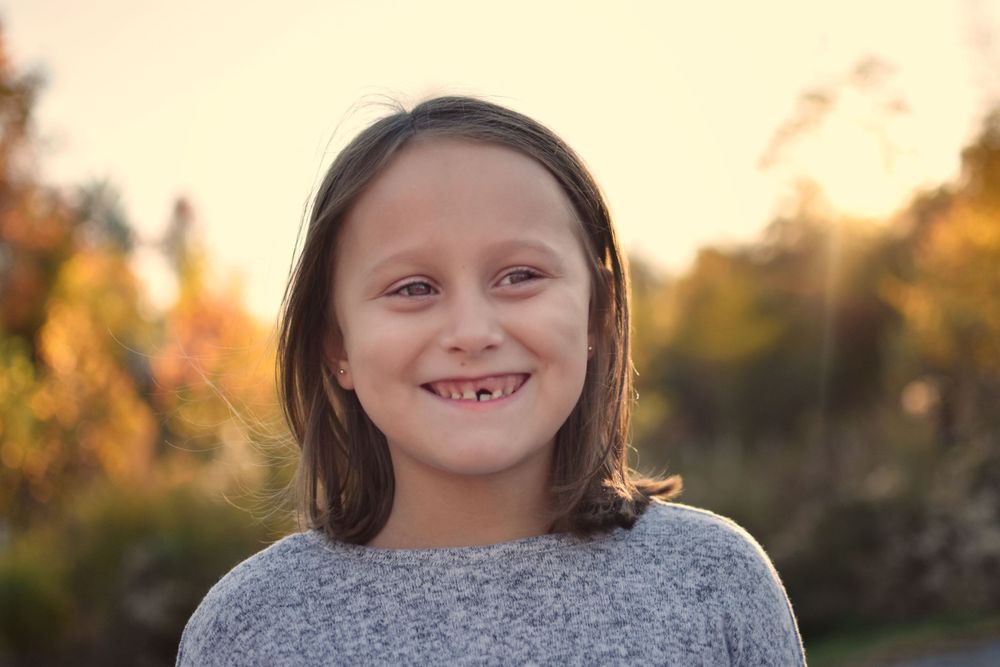 School aged girl in gray with fall foilage, sunset