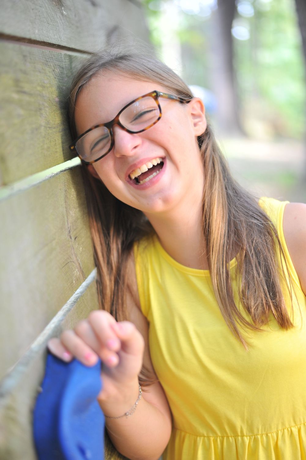 Teen, tween school girl laughing at wood wall in yellow