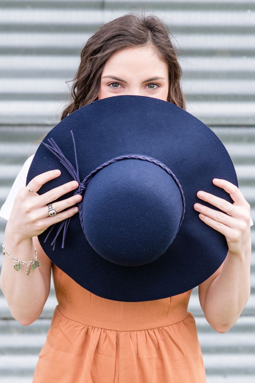 A playful portrait showing someone peeking over a large navy blue hat.