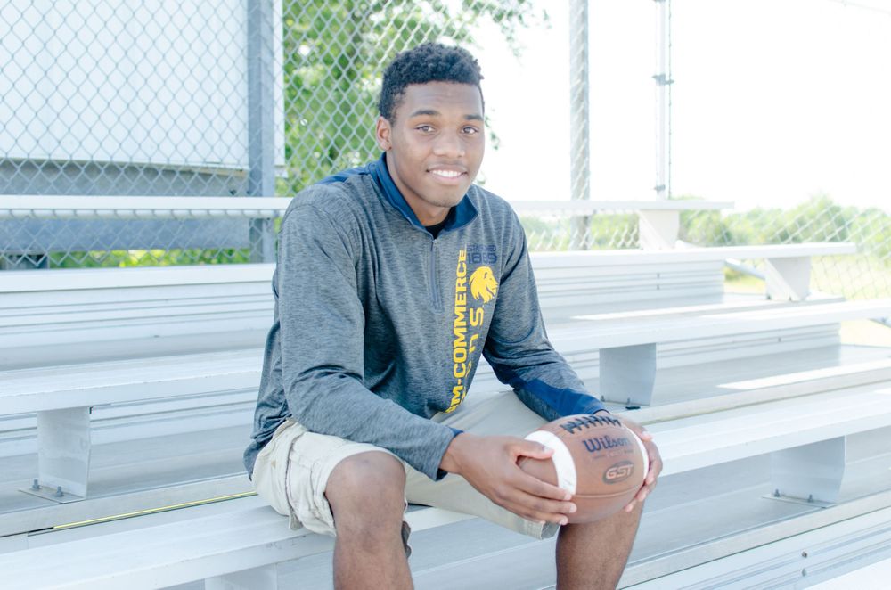 Athletic person in grey hoodie sitting on metal bleachers.