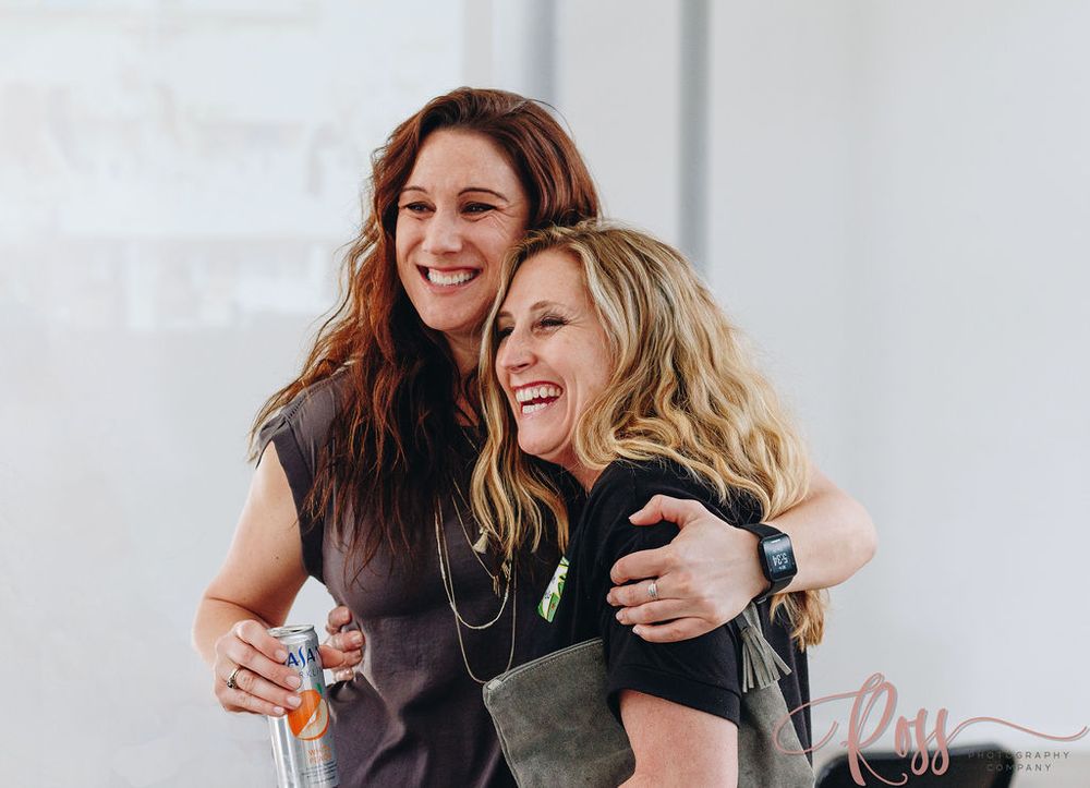 Two friends laughing and embracing while spending time together outdoors.