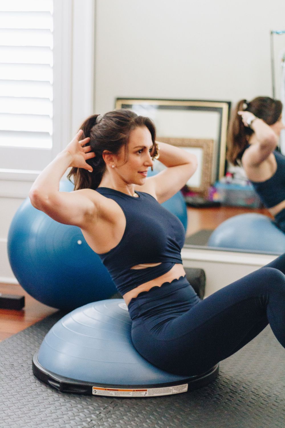 Person exercising on blue stability ball in home gym setting.