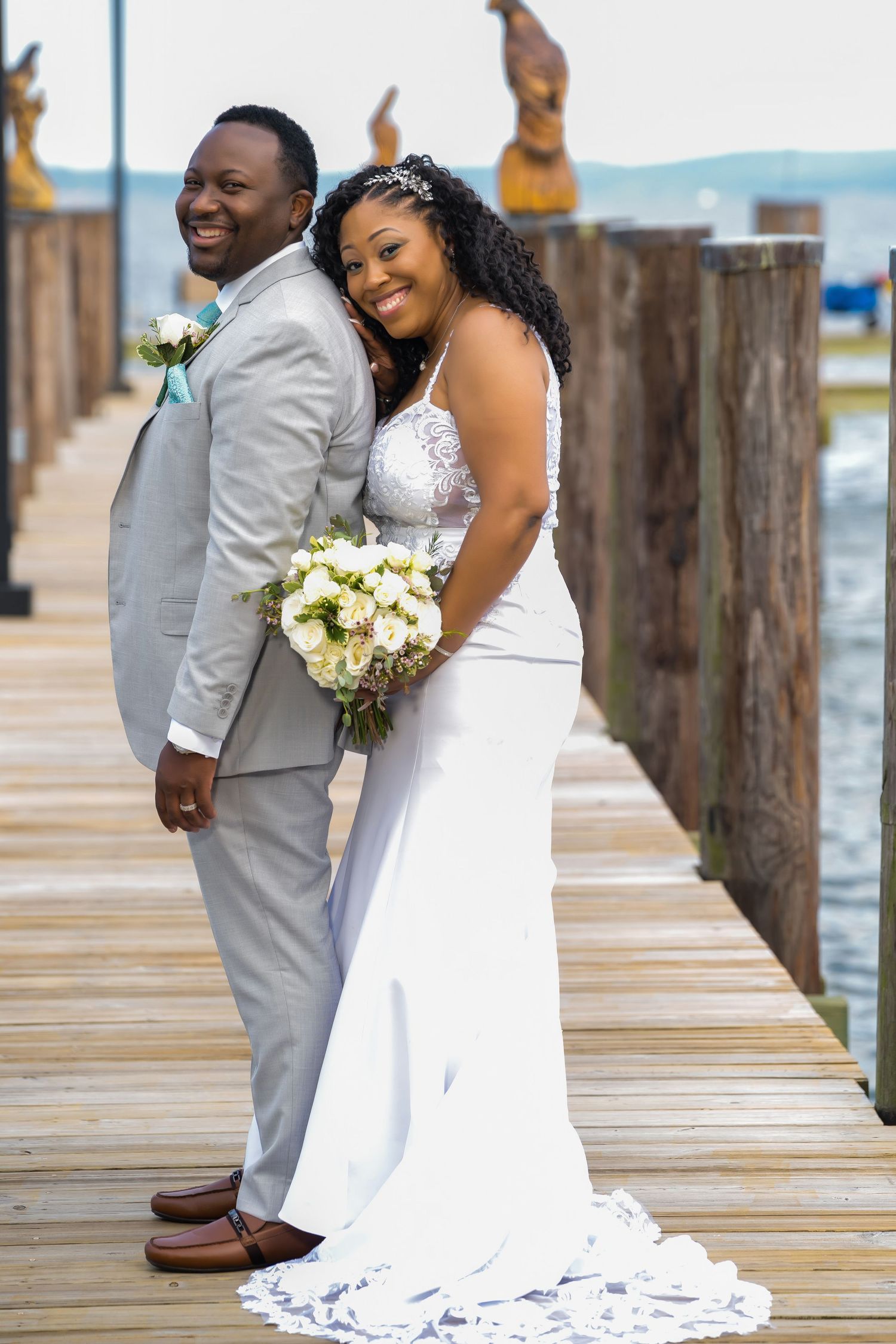 A happy couple shares a moment together on a waterfront boardwalk.