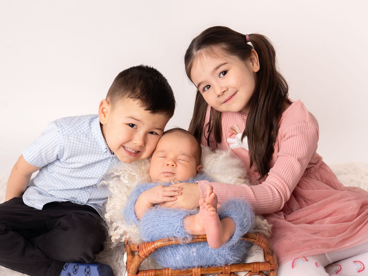 Sibling photo of brother and sister, with newborn baby sleeping in basket by newborn photographer in Doncaster.