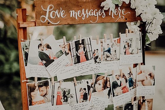 Rustic wooden wedding guest book display with polaroid photos and love messages on string clips.