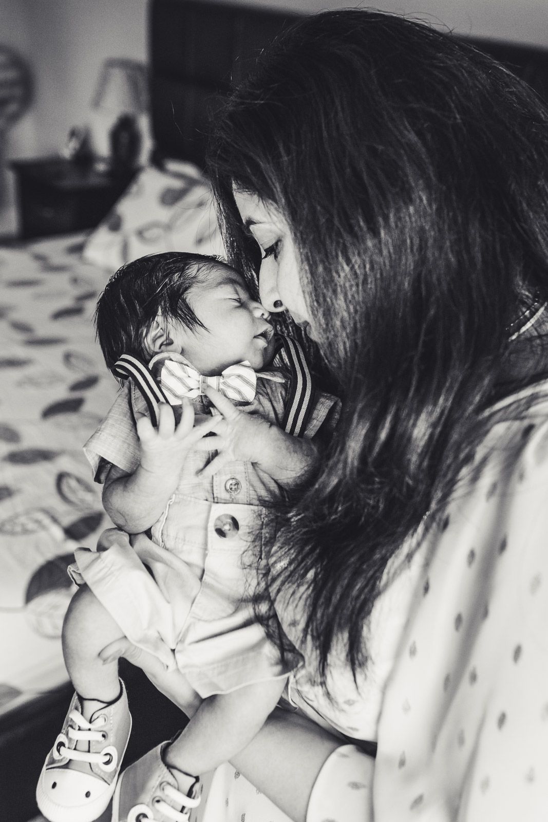 Black and white photo of mother providing nose kisses to newborn baby