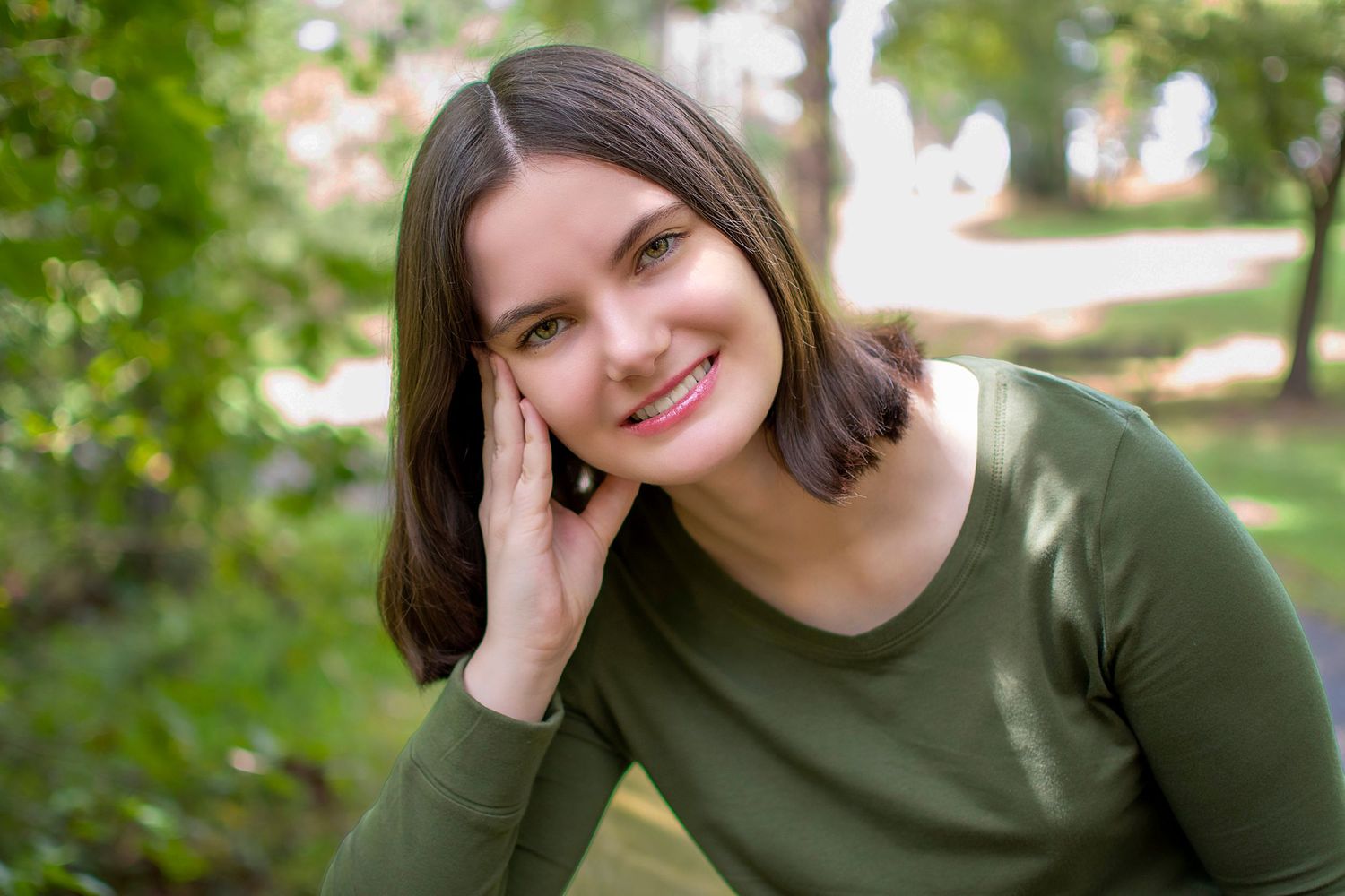 Outdoor headshot of person in olive green sweater during golden hour.