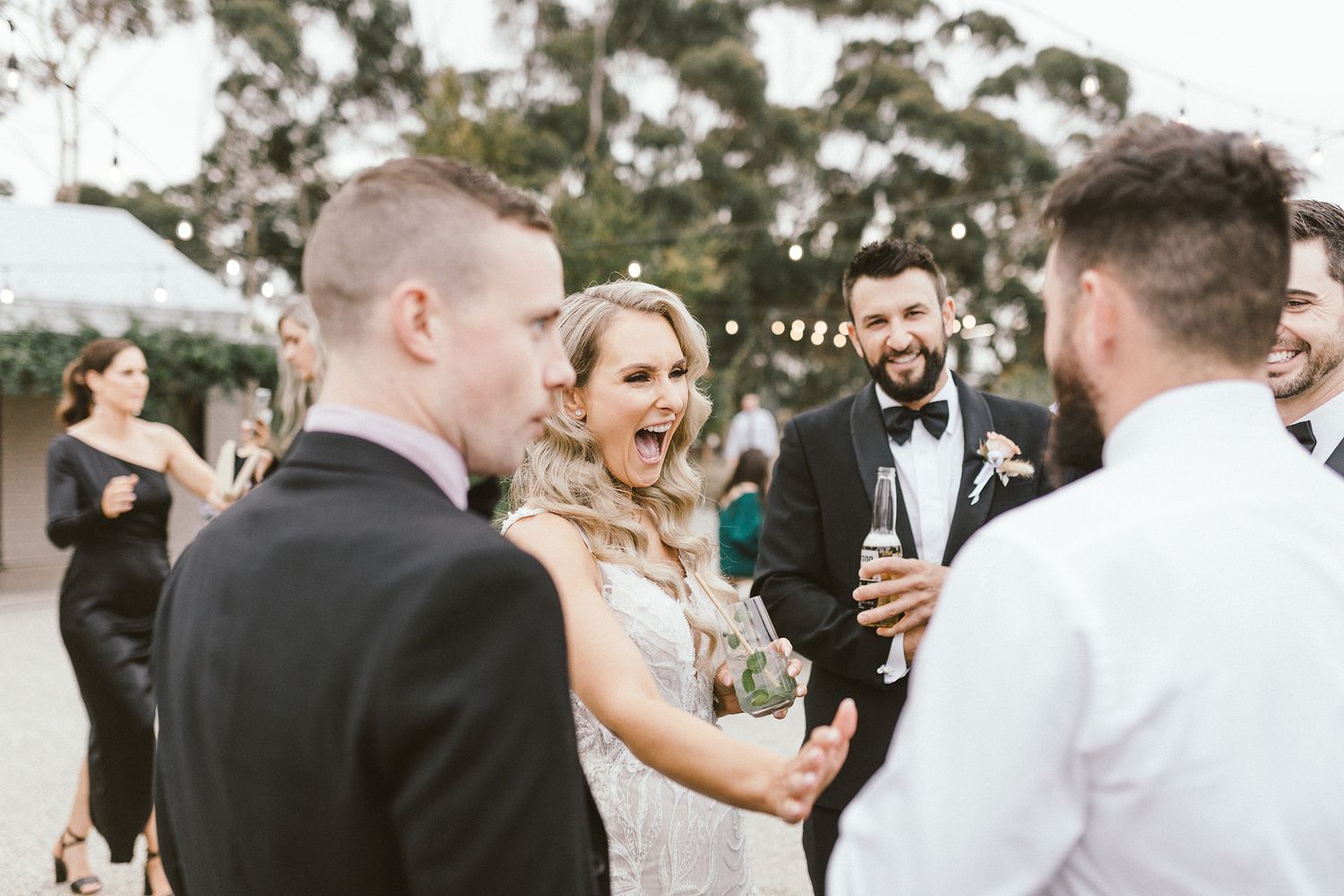 Wedding party sharing a lighthearted moment during outdoor celebration.