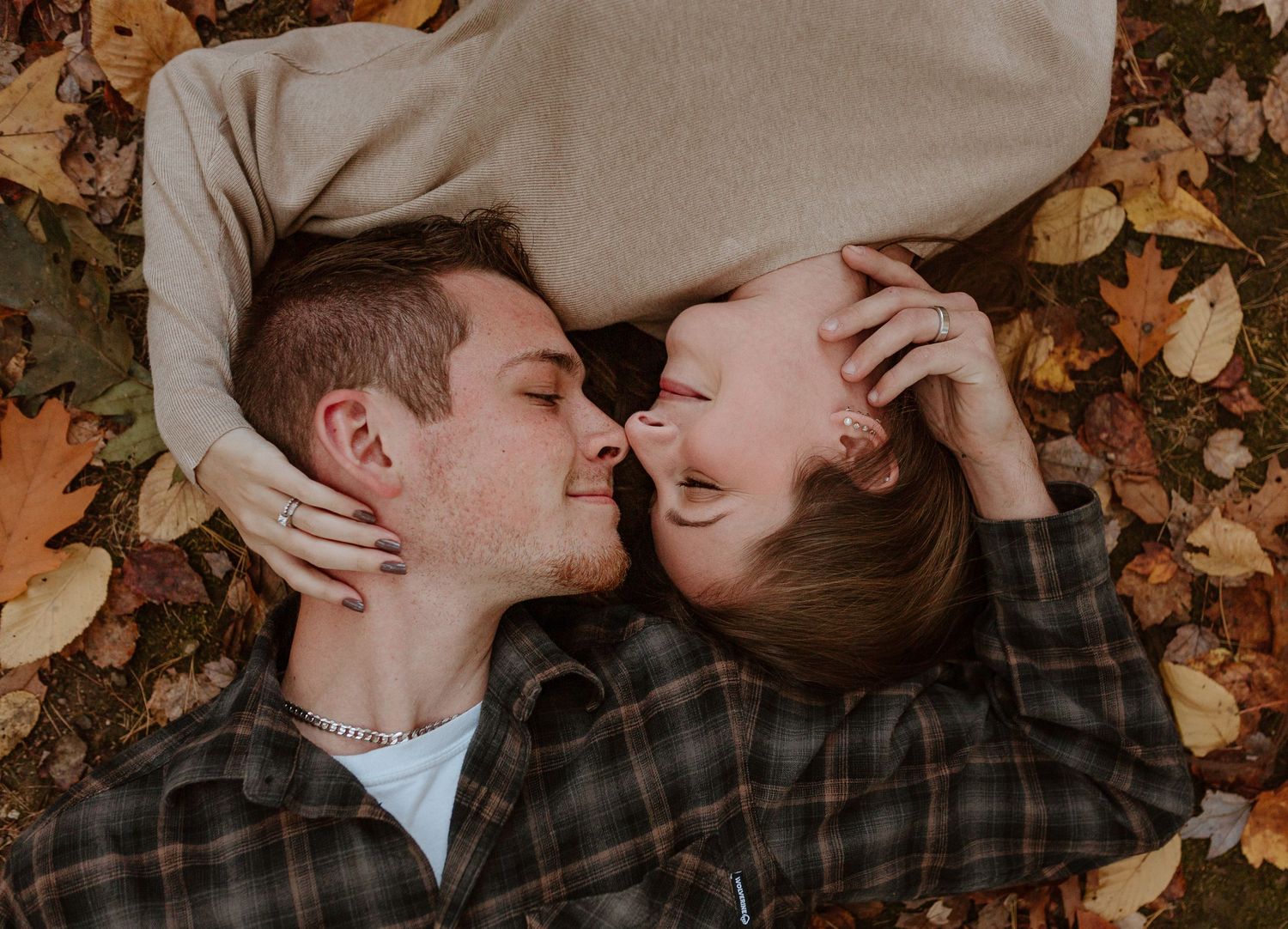 Fall engagement photo session in Connecticut. couple is laying in the leaves giving each other nose kisses