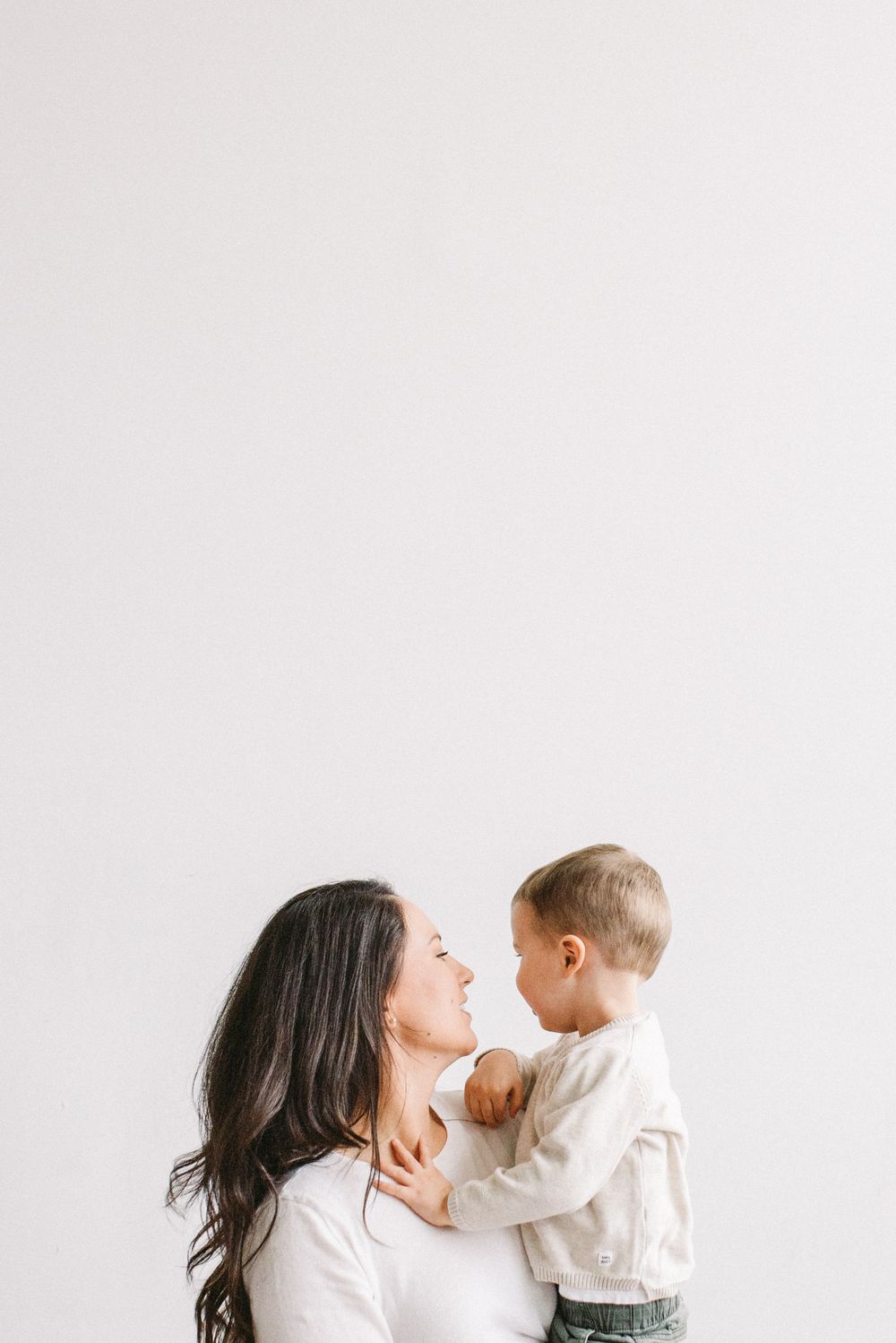 A tender moment shared between parent and toddler against a minimalist white backdrop.