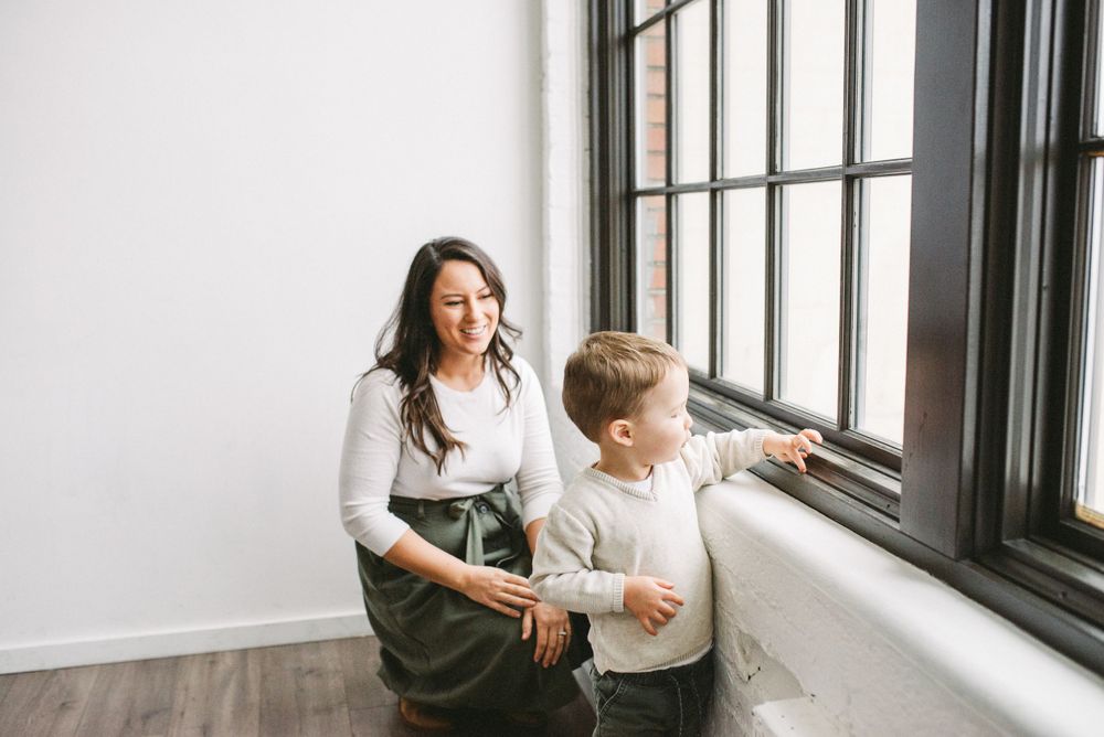 Adult and child looking out large window together in minimalist room.