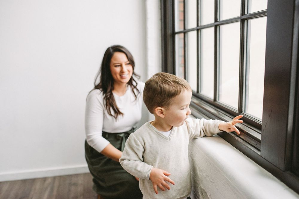 Adult and child exploring view through modern window with natural lighting.