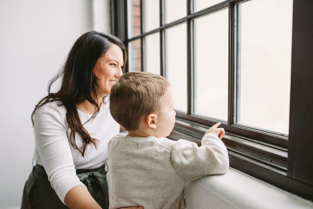 Sweet bonding moment as adult and child gaze through window together.