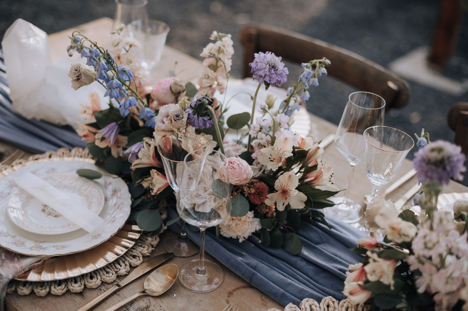 Elegant table decor with blush and blue flowers, gold charger plates, and navy blue accents.