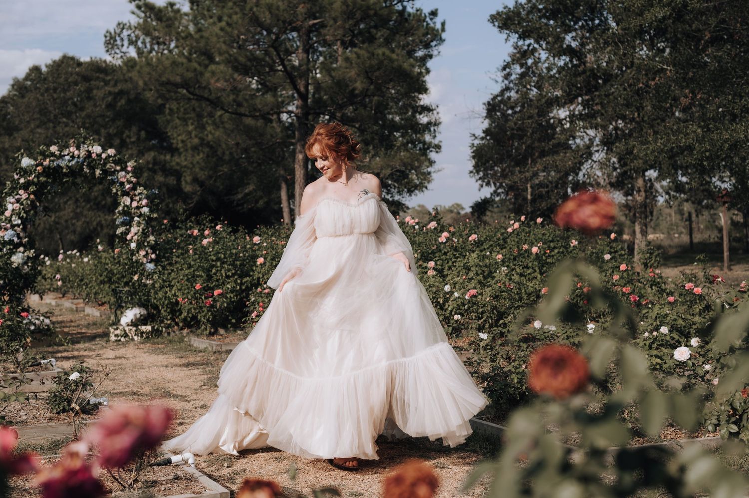 Dreamy bridal portrait in a rose garden with white flowing dress and natural lighting.