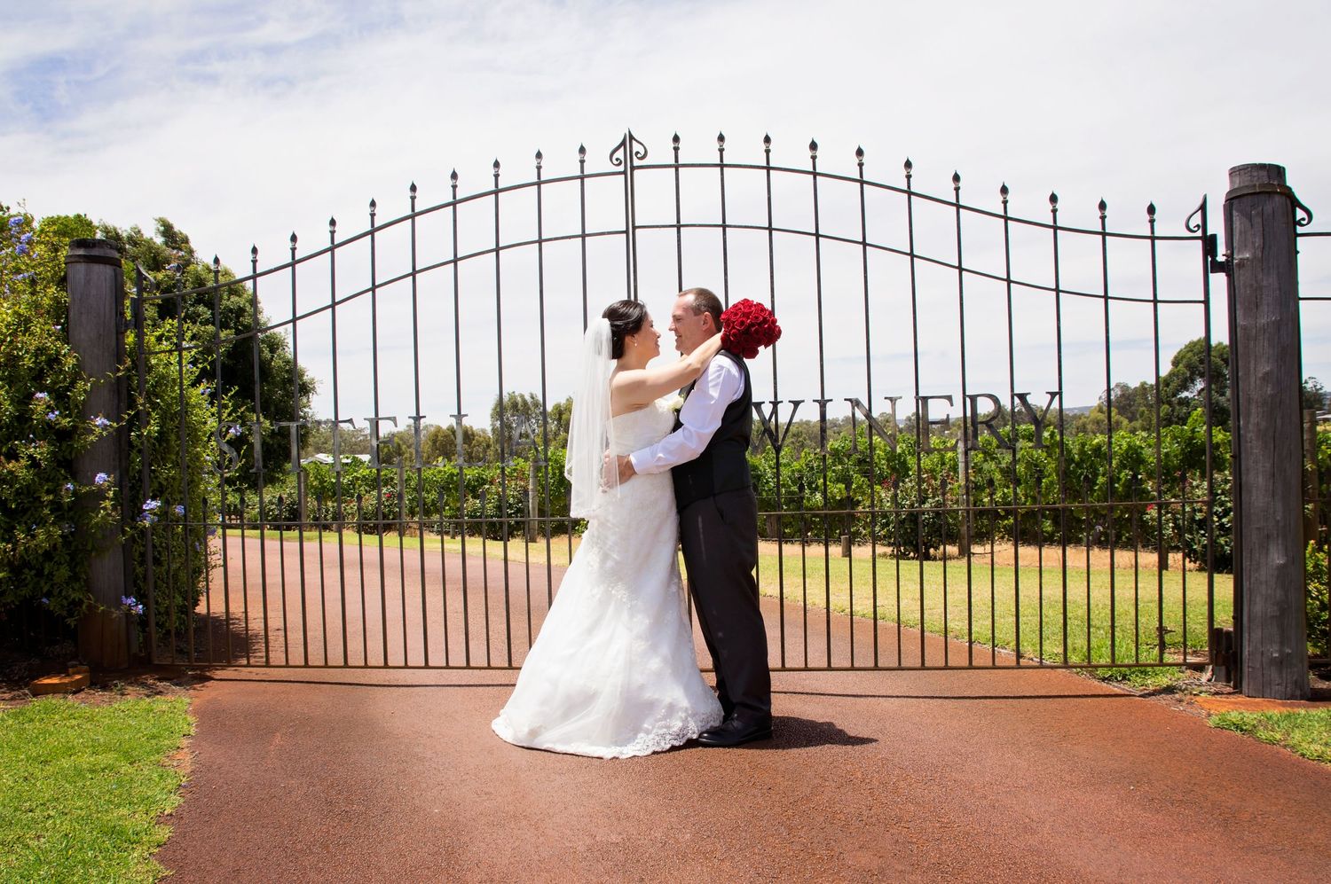 bride and groom posing infront of sitella winery gate