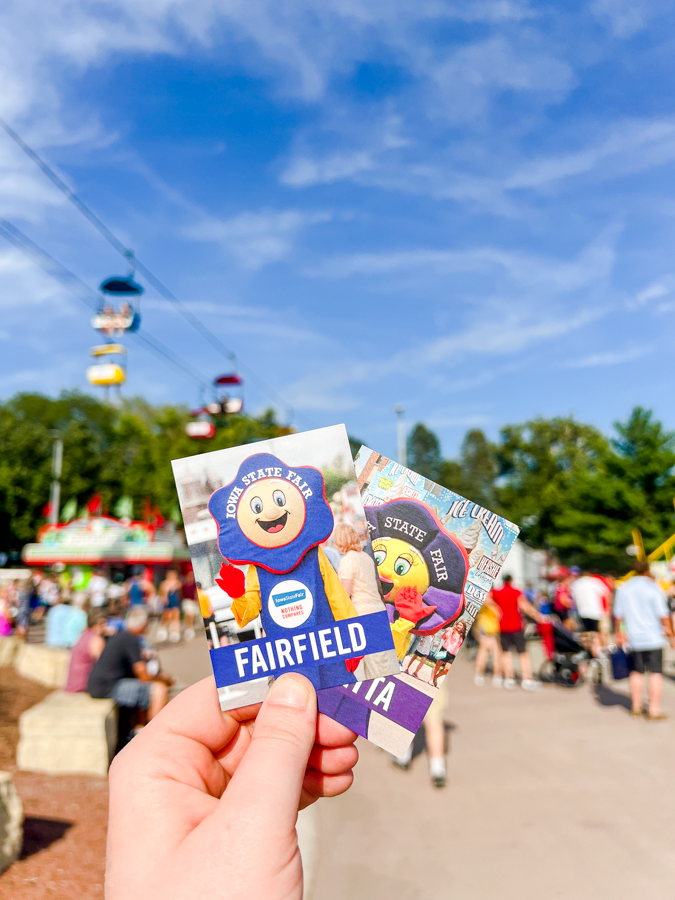 Hand holding Fairfield themed amusement park tickets against a blue summer sky.