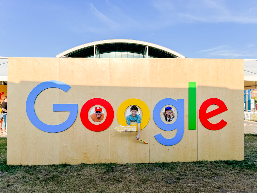 Long Google logo painted on a beige wall with colorful letters.