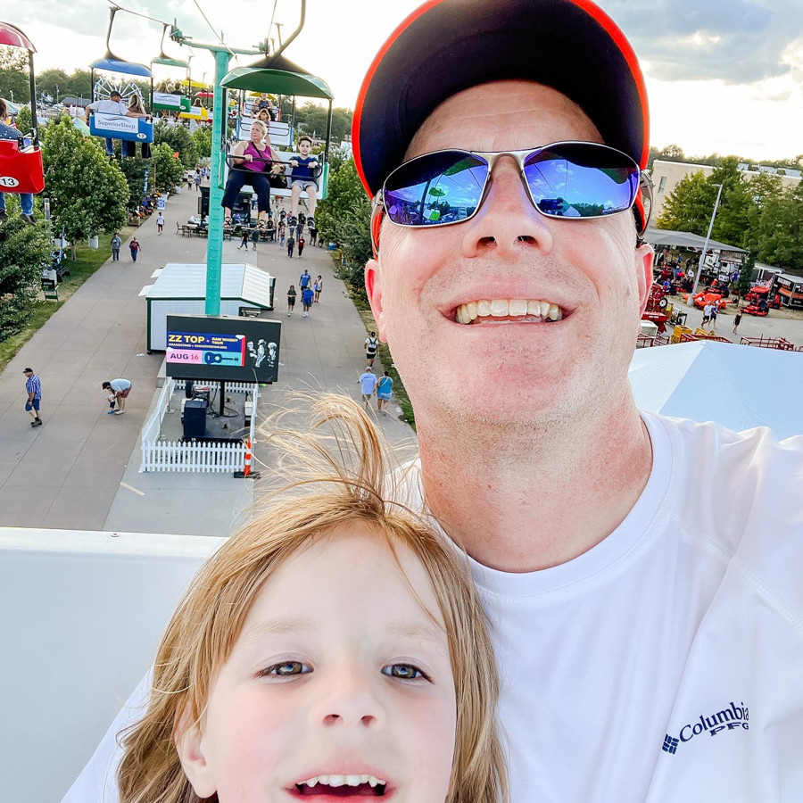 Two people enjoying a sunny day at an amusement park with blue sky in the background.