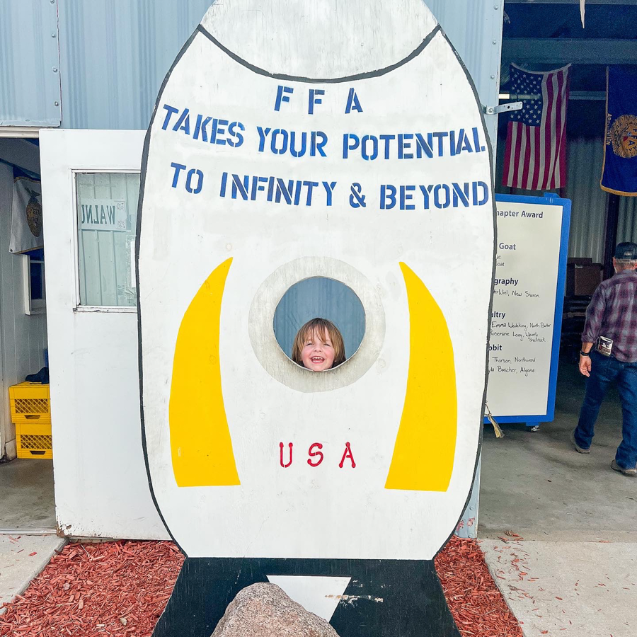 Space-themed photo opportunity board with USA and FFA text at a carnival.