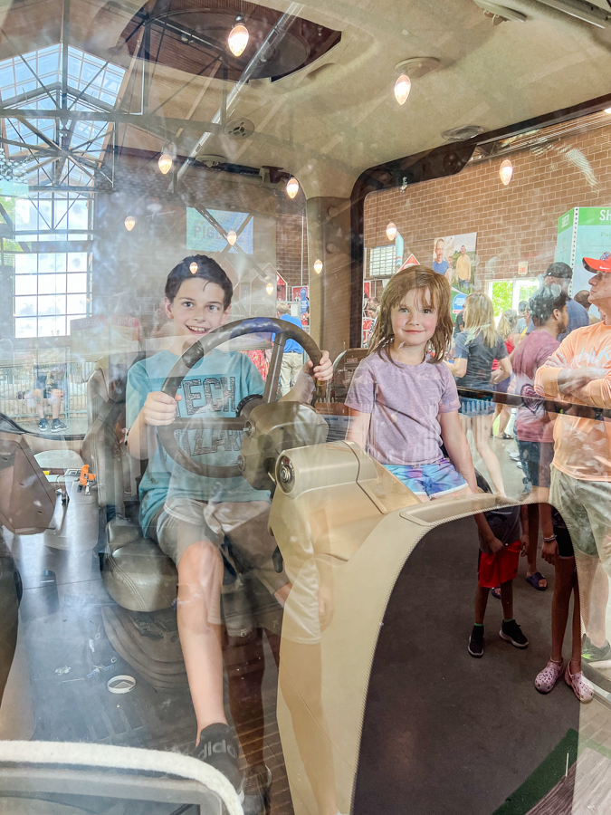 Children sitting inside a vintage train car display at a museum or exhibition.