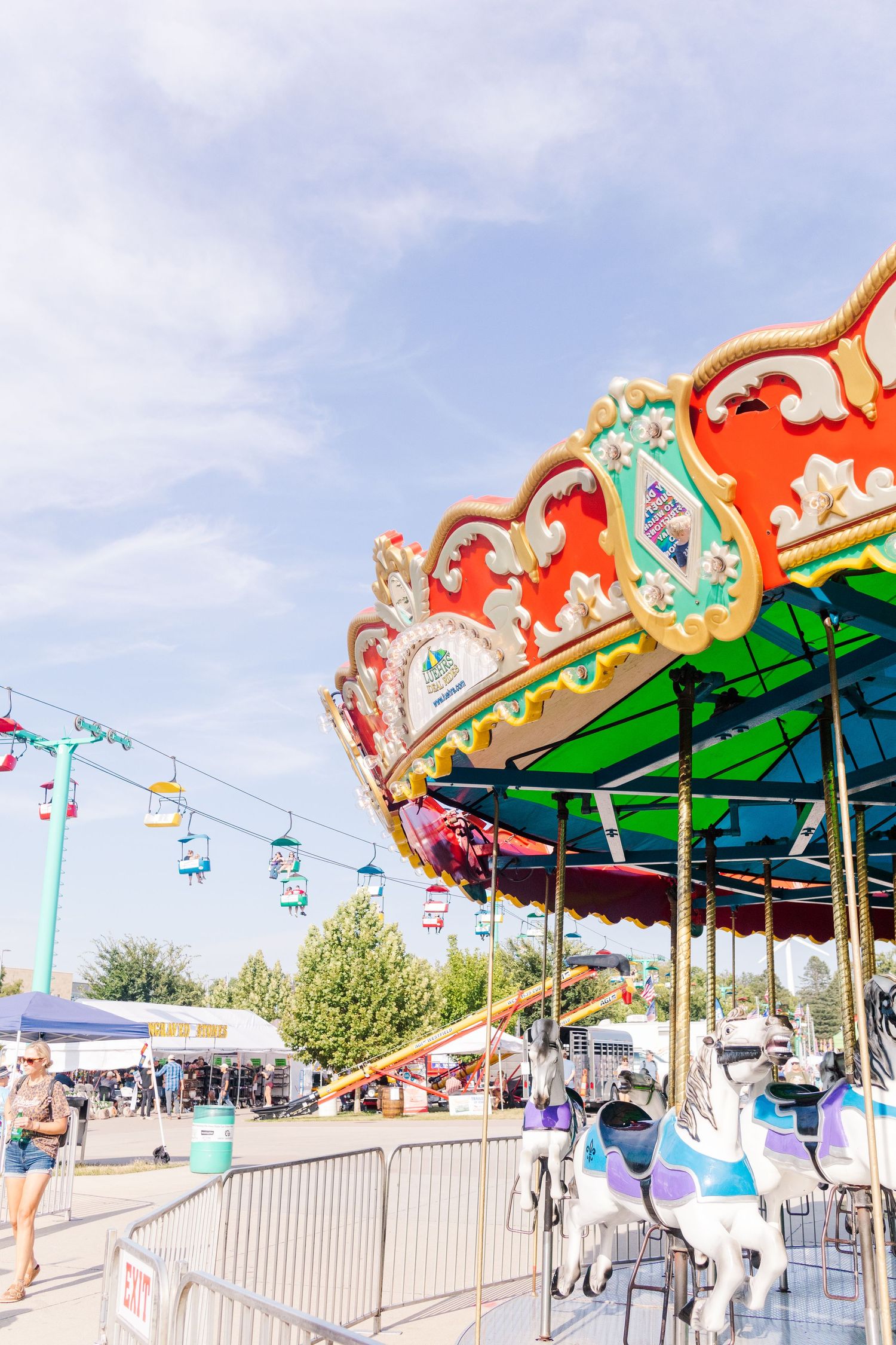 Ornate carnival carousel canopy with decorative trim against a blue sky.