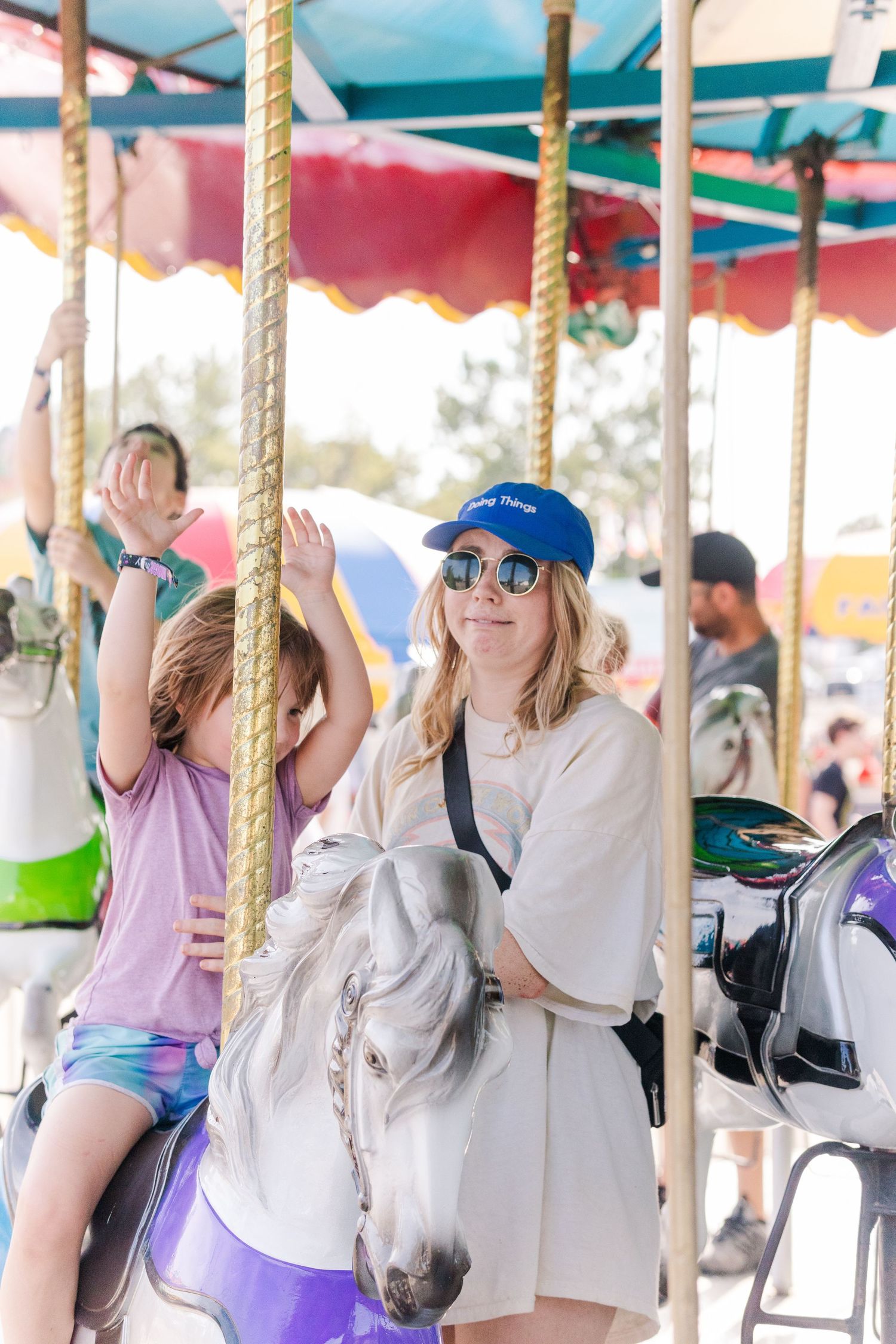 People enjoying a colorful carousel ride with decorative horses at a carnival or fair.