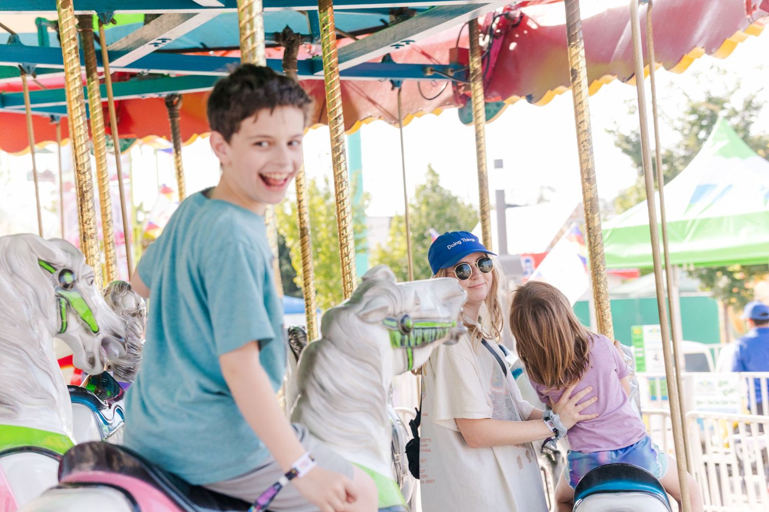 Children riding on a traditional merry-go-round carousel with white horses at an amusement park.