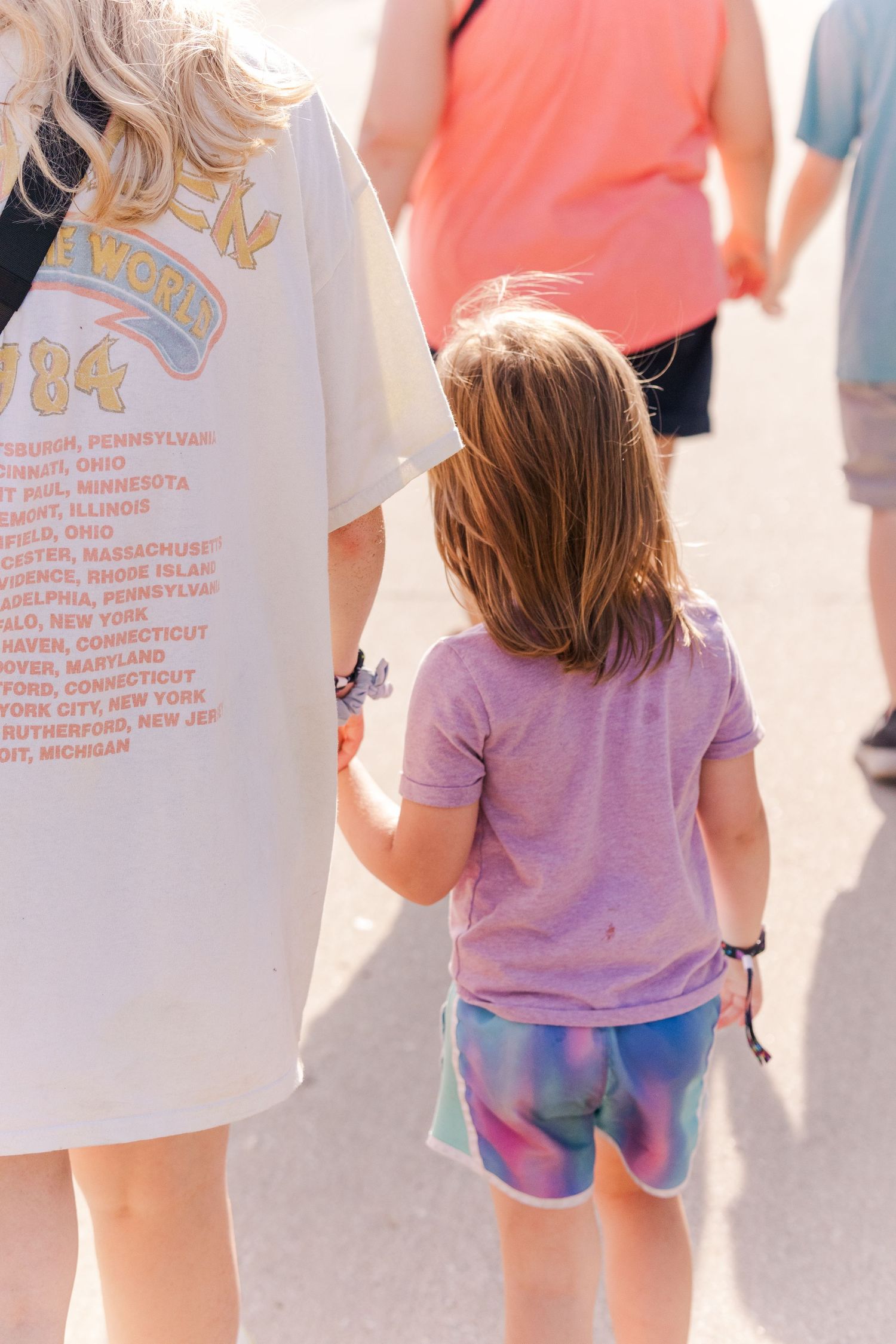 People walking through a summer fair wearing colorful casual clothing.