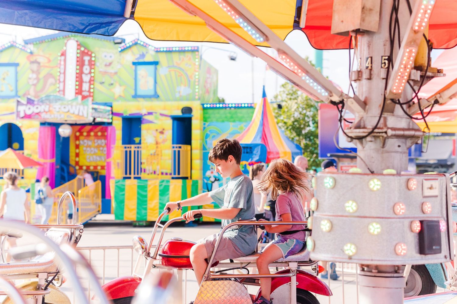 Colorful carnival ride with bright umbrellas and decorative elements against a blue sky at an amusement park.