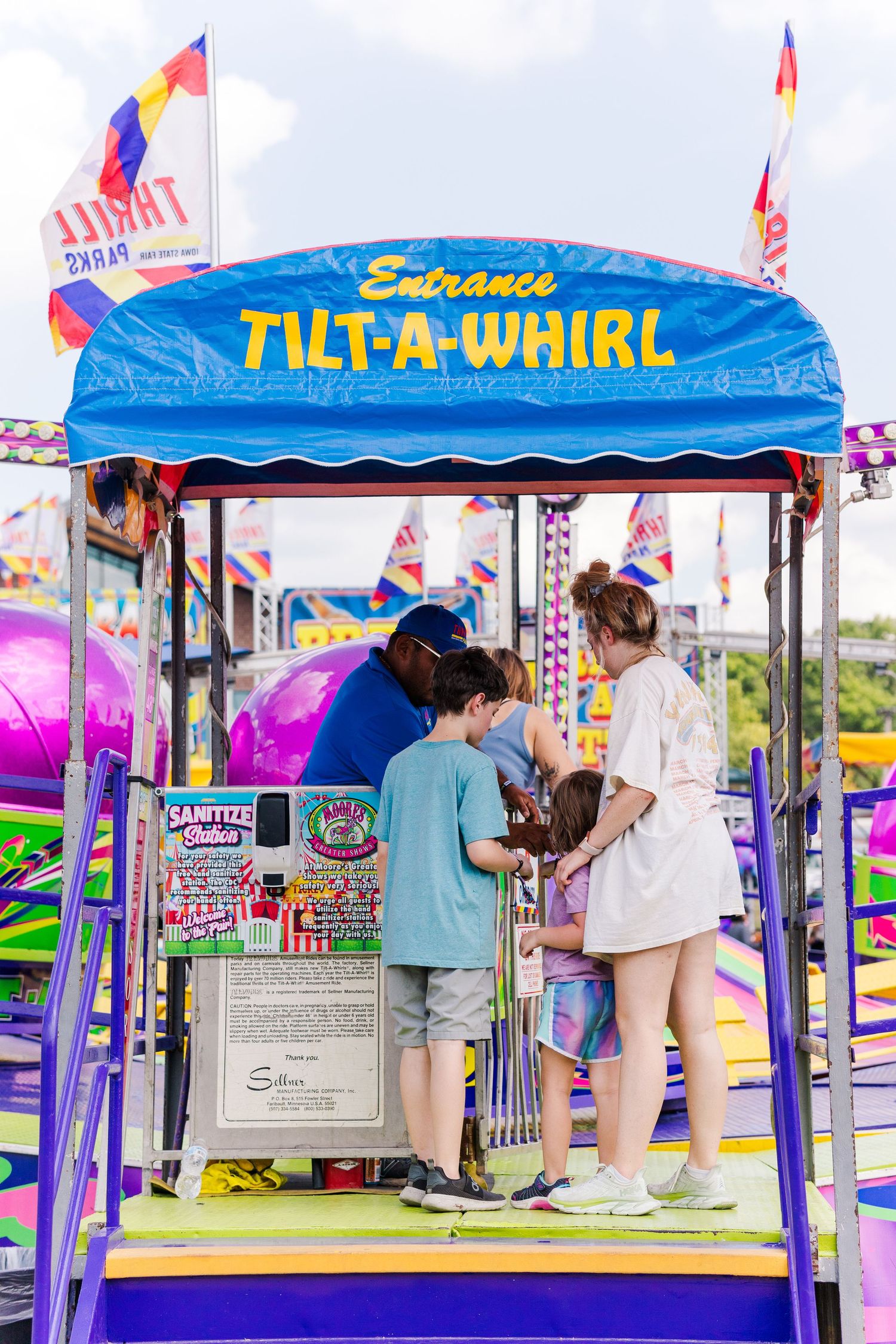 Entrance to the Tilt-A-Whirl carnival ride with colorful signage and flags.