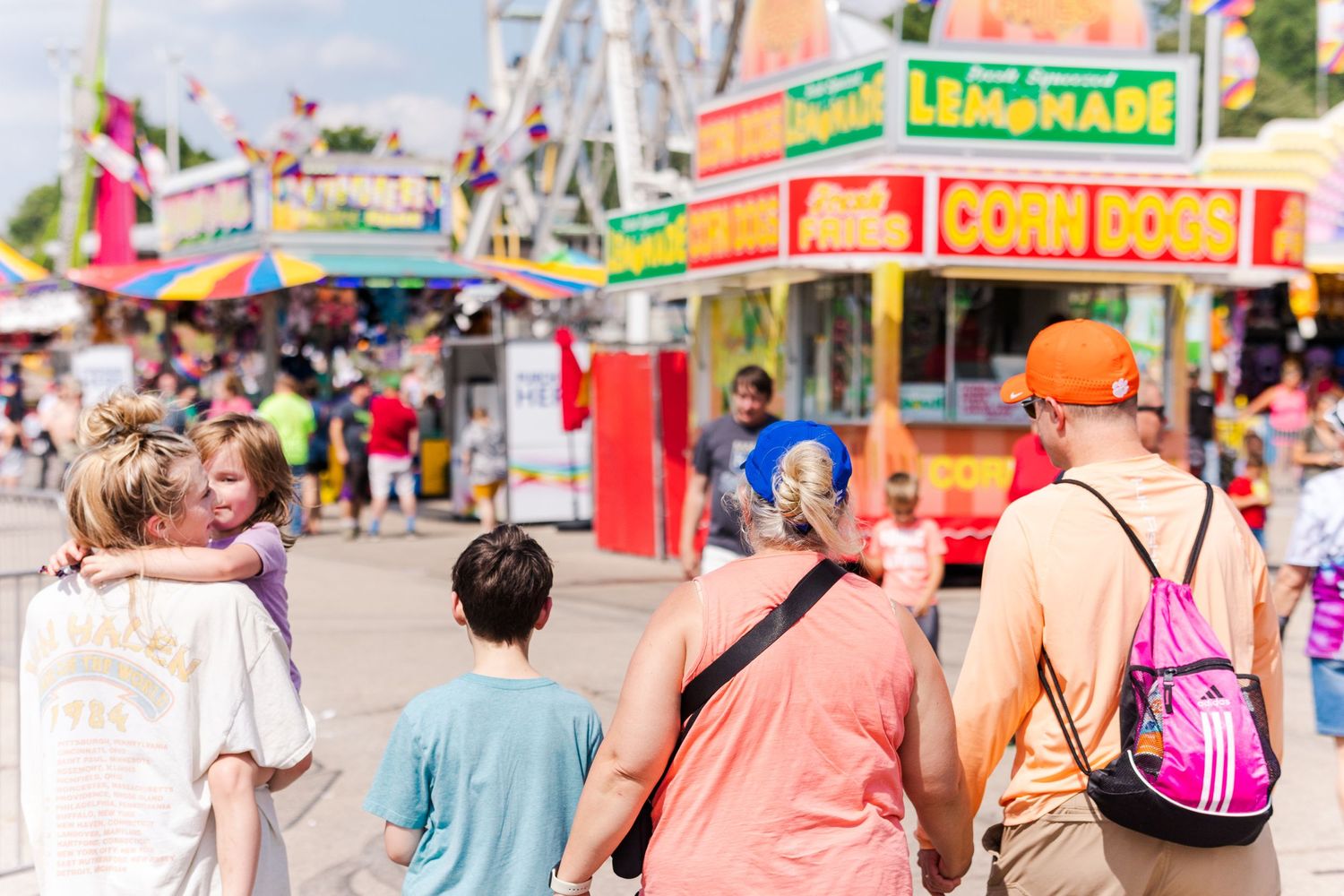 Colorful carnival game booths with vibrant signs and decorations line a fairground midway.