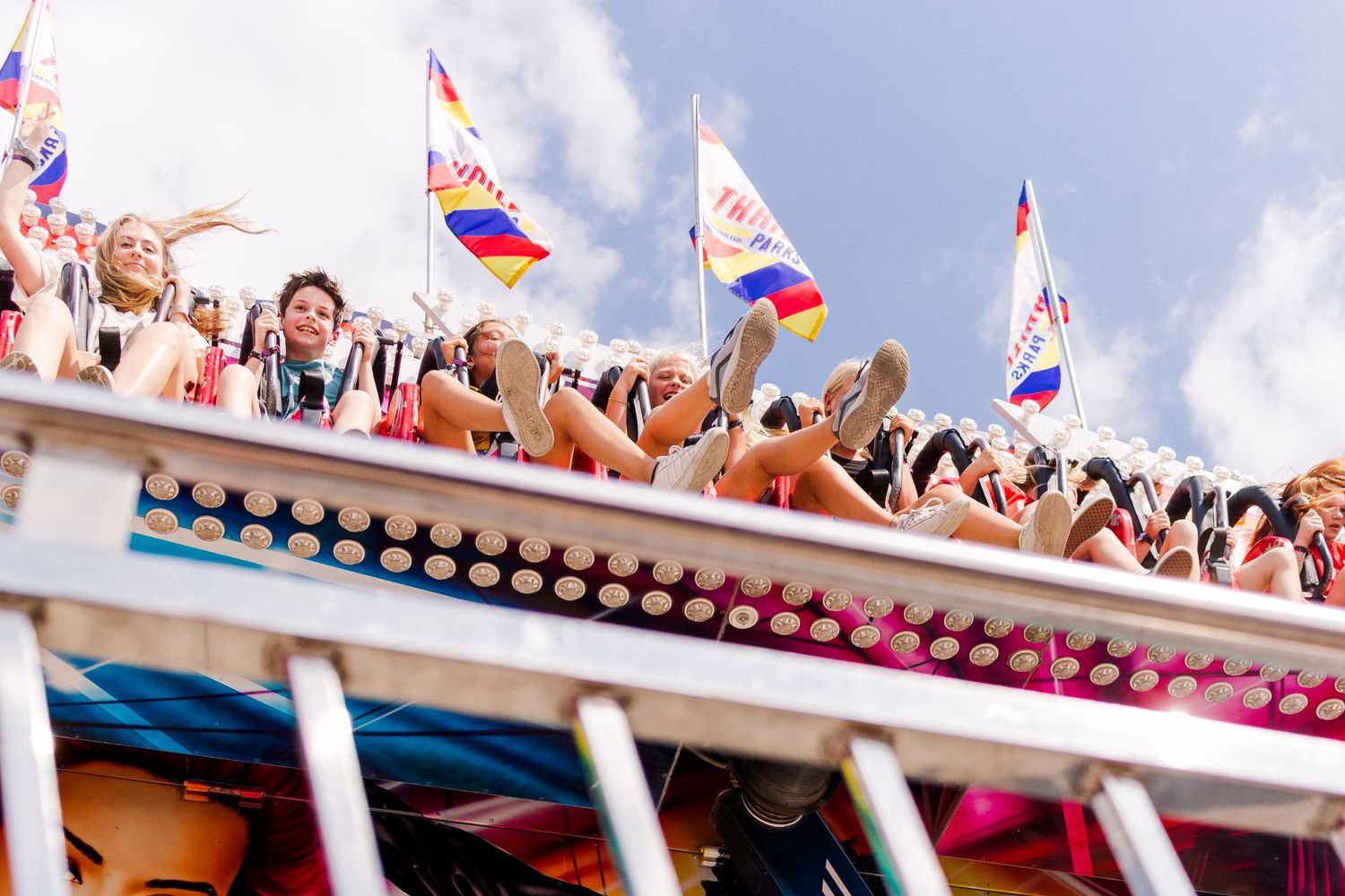 Festive carnival flags and banners wave above crowded fairground attractions.