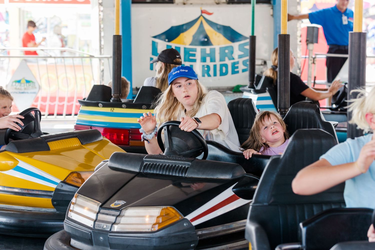Fairgoers enjoying bumper cars at an amusement park ride attraction.