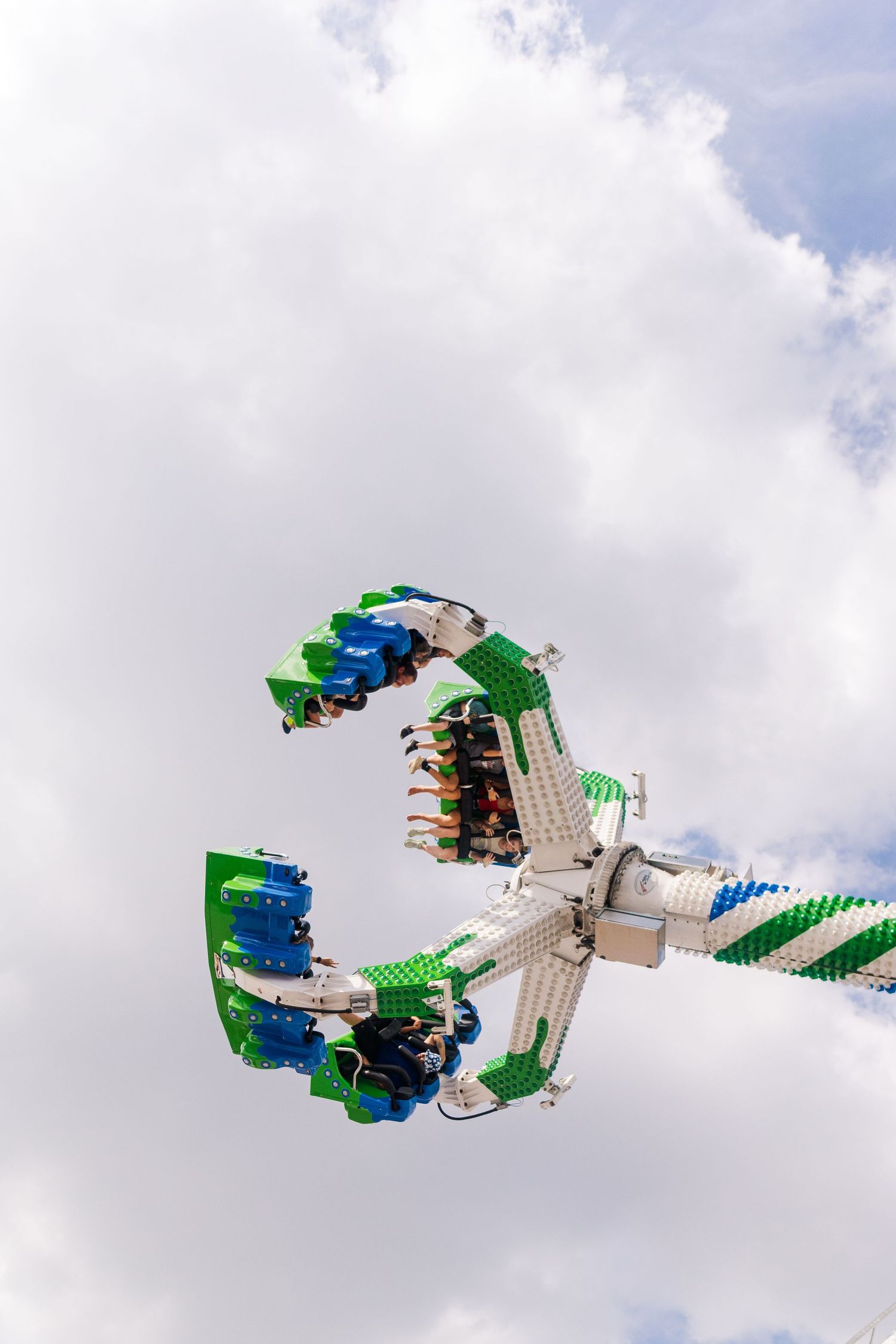 Amusement park thrill ride spinning through the air against cloudy sky.