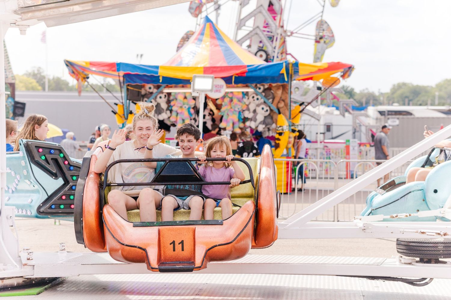 Riders enjoying a classic orange carnival ride with spinning seats at an outdoor fair.